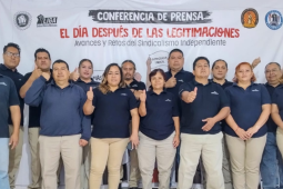 St Gobain workers stand in front of a large banner reading: Press Conference—The Day After Contract Legitimations; Advances and Challenges in Independent Unionism