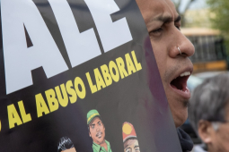 A man yells while holding a sign saying DALE ‘Alto Al Abuso Laboral’ (DALE stop workplace abuses)