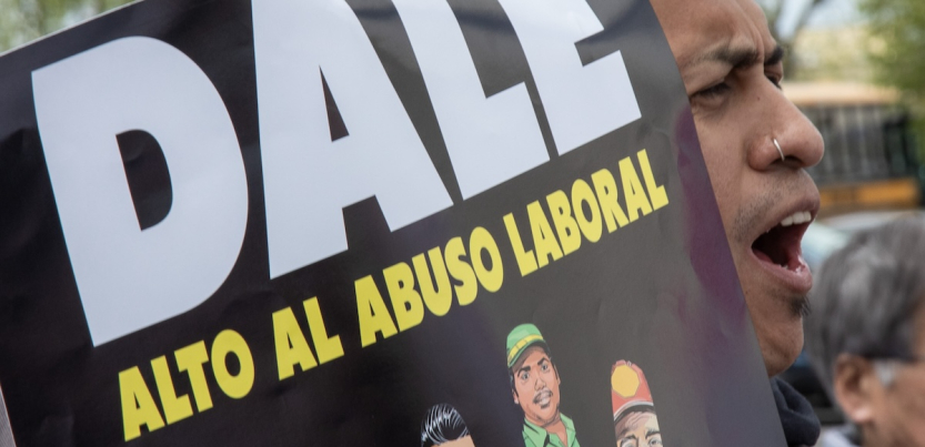 A man yells while holding a sign saying DALE ‘Alto Al Abuso Laboral’ (DALE stop workplace abuses)