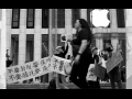 People march in front of an Apple store in New York City, holding signs and banners in English and Chinese. Their faces are blurred out in the photo due to fears of retaliation from the Chinese government against them and their families.