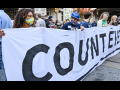 A group of people holds a large white banner with the slogan Count Every Vote.