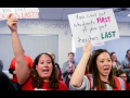 Two teachers holding signs. Tiffany's sign says "You can't put students first if you put teachers last."