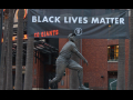 A Black Lives Matter banner hangs behind a statue of Willie Mays at Oracle Park.