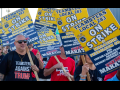 White and Black men and women march with picket signs that say "Teamsters Local 238, Marathon Petroleum Co, Unfair Labor Practices against Detroit refinery workers." Most of those whose T-shirts are visible are wearing messages like "Teamsters against Trump," "Trump is a scab," and "Harris-Walz" with an IBT local logo.