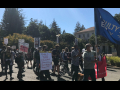 A group of students and lecturers march holding banners and signs.