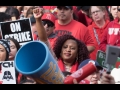 Black woman raising her fist in a crowd of strikers