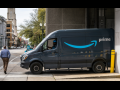 Amazon van exiting a building, about to turn onto a city street, with pedestrian crossing in front