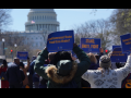 Crowd of people viewed from behind, holding blue AFGE sign. One says "Proud Government Worker, Proud Union Member. Another says "Stand, Unite, Fight." In front of them is the U.S. Capitol building.