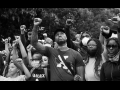 Black and white photo of a crowd people, mostly Black, various ages, all with fists raised in the air.