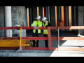 Two construction workers looking down in building construction site with wooden scaffolding around them.