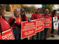 Dedham educators in red, on a picket line, with red and white signs.