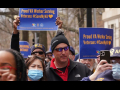 several people are jammed together as part of a march with blue signs with gold lettering, saying “Proud VA Worker Serving Veterans, #SaveMyVA”