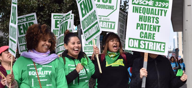 Four women carrying picket signs for AFSCME 3299 strike