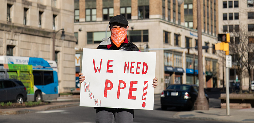 CWA protester holding a sign that says "We Need PPE"