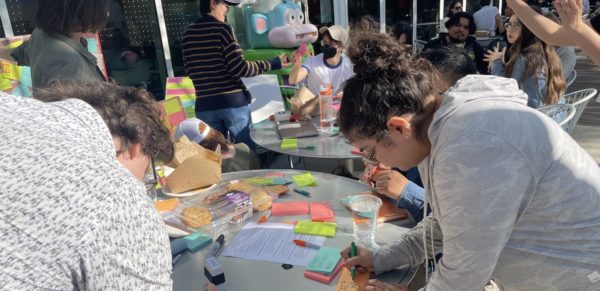 A group write colorful post-in at outside round tables--one says bereavement leave