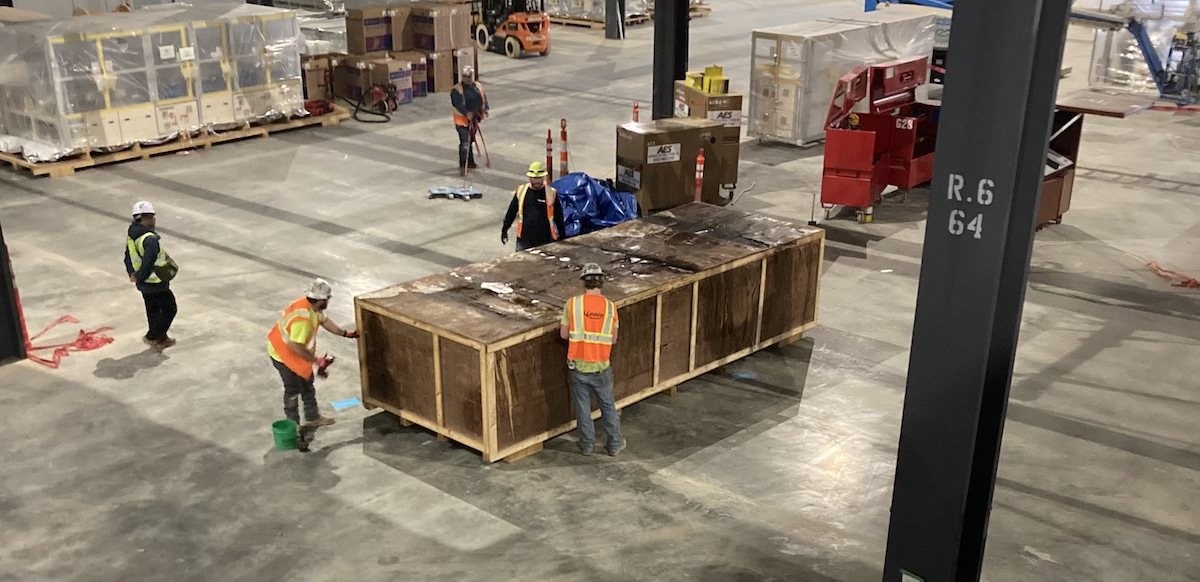 Several workers work around a crate with black-colored mold visible on the lid