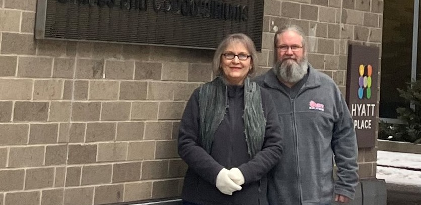 A couple stand by a wall with a Hyatt sign