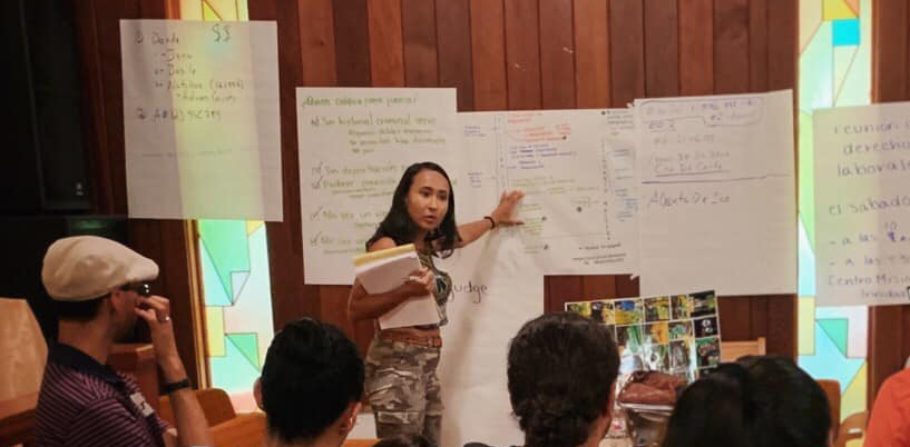 Woman leads organizing meeting from front of room.