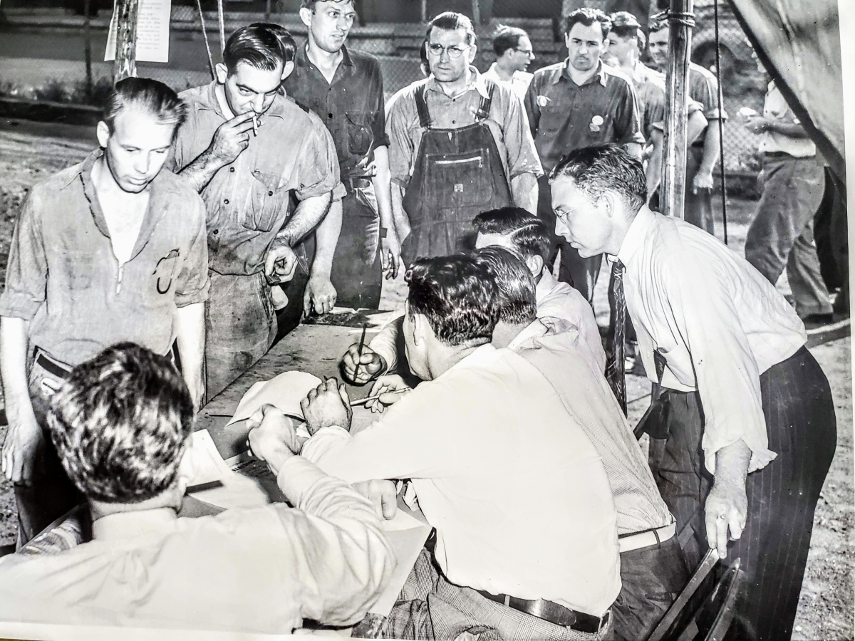 Workers—in their soiled work clothes—line up to vote at a table in a 1941 union election.