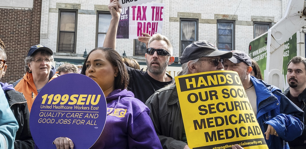 Several demonstrators gather with various signs about Medicaid and Social Security