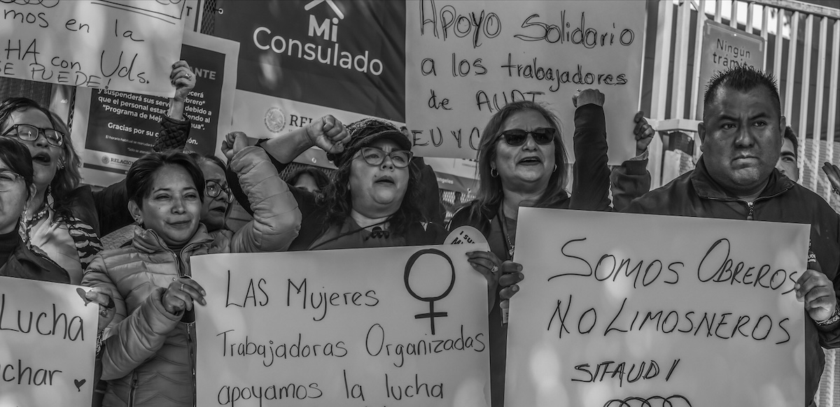 Workers hold signs in Spanish saying ‘we are workers not beggars’.