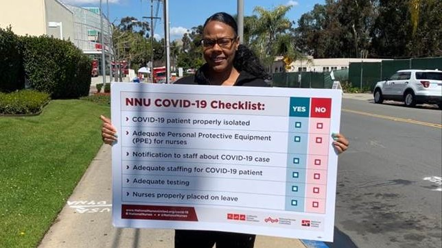 A nurse holds a sign showing "NNU COVID-19 Checklist: patient properly isolated, adequate PPE for nurses, notification to staff about case, adequate staffing for patient, adequate testing, nurses properly placed on leave"