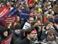 A sea of faces in a protest crowd. Some printed signs say "Stop the Billionaire Takeover," "Hands Off Workers Data," "Stand, Unite, Fight," and "Nobody Elected Musk." Some handlettered signs say "Congress, WYA?" and "He doesn't even go here!"