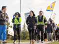 Workers silhouetted against the sky march forward in a line, smiling. Some hold "CUPW" flags aloft. The view is looking up from near the ground, giving them a heroic vibe.