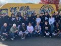 Thirty people pose with a yellow van behind them that says One Union, One Family