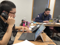 Three union activists sit around a table on their phones, making calls to drum up support for Initiative 1.