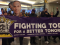 Commercial office janitors, retail janitors, security officers, window cleaners, and airport workers march through the downtown Minneapolis skyway, carrying a banner that reads "Fighting Today for a Better Tomorrow," as part of SEIU Local 26's contract campaign.