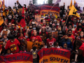 A diverse crowd of people, viewed from above, fills the frame. Most people are wearing red shirts. Many are Black. Many are lifting flags or raised fists and some hold "Organize the South" banners. Many little kids are in the front of the crowd.