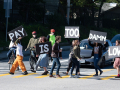 grad students blocking traffic in the street with signs that read "The Pay Is Too Damn Low"