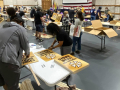 IATSE preparing picketing signs on tables in rows in room with gray floor.