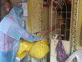 Dalit sanitation worker in a PPE suit accepting trash in yellow bags by hand from the home of a coronavirus patient