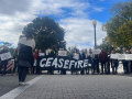 A group of people hold a black banner that says CEASEFIRE.