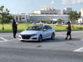 Workers outside a big plant approach a car with leaflets.