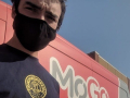 A bikeshare driver wearing a black mask stands in front of a red MoGo van.