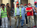 A group of mainly Pakistani immigrant workers stand at a rally while a union organizer speaks through a bullhorn.