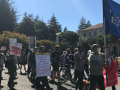 A group of students and lecturers march holding banners and signs.