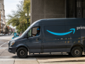 Amazon van exiting a building, about to turn onto a city street, with pedestrian crossing in front