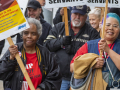 Postal workers march with signs about working conditions.